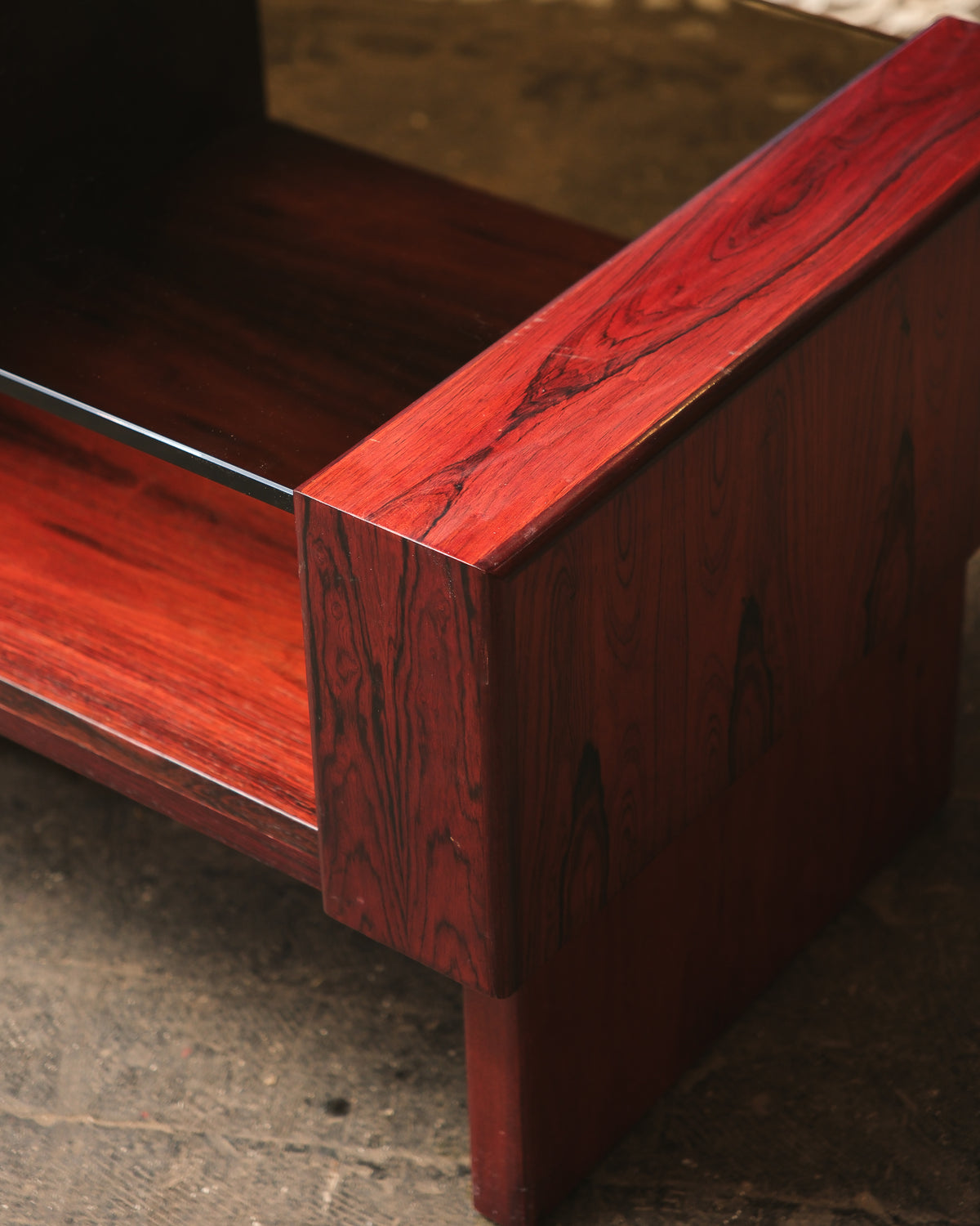 Detail of the rosewood grain and glass edge at the table's corner.