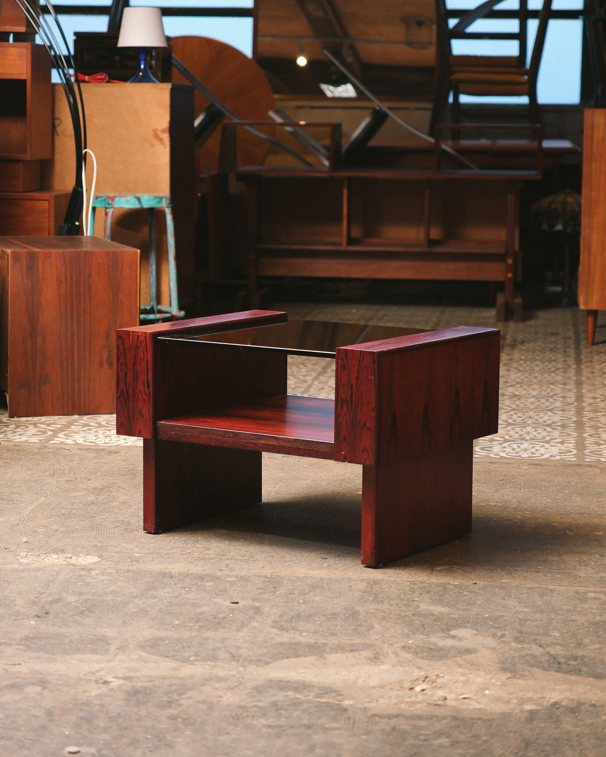 Side view of the rosewood coffee table with smoked glass top in a showroom.