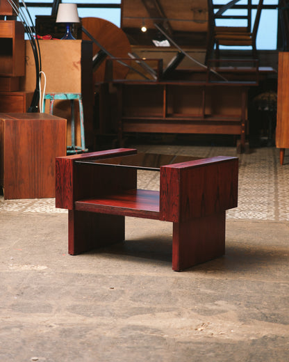 Side view of the rosewood coffee table with smoked glass top in a showroom.
