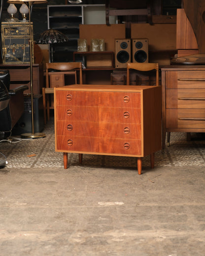 Front view of mid-century modern teak 4-drawer dresser with oval pulls, shown in showroom setting.