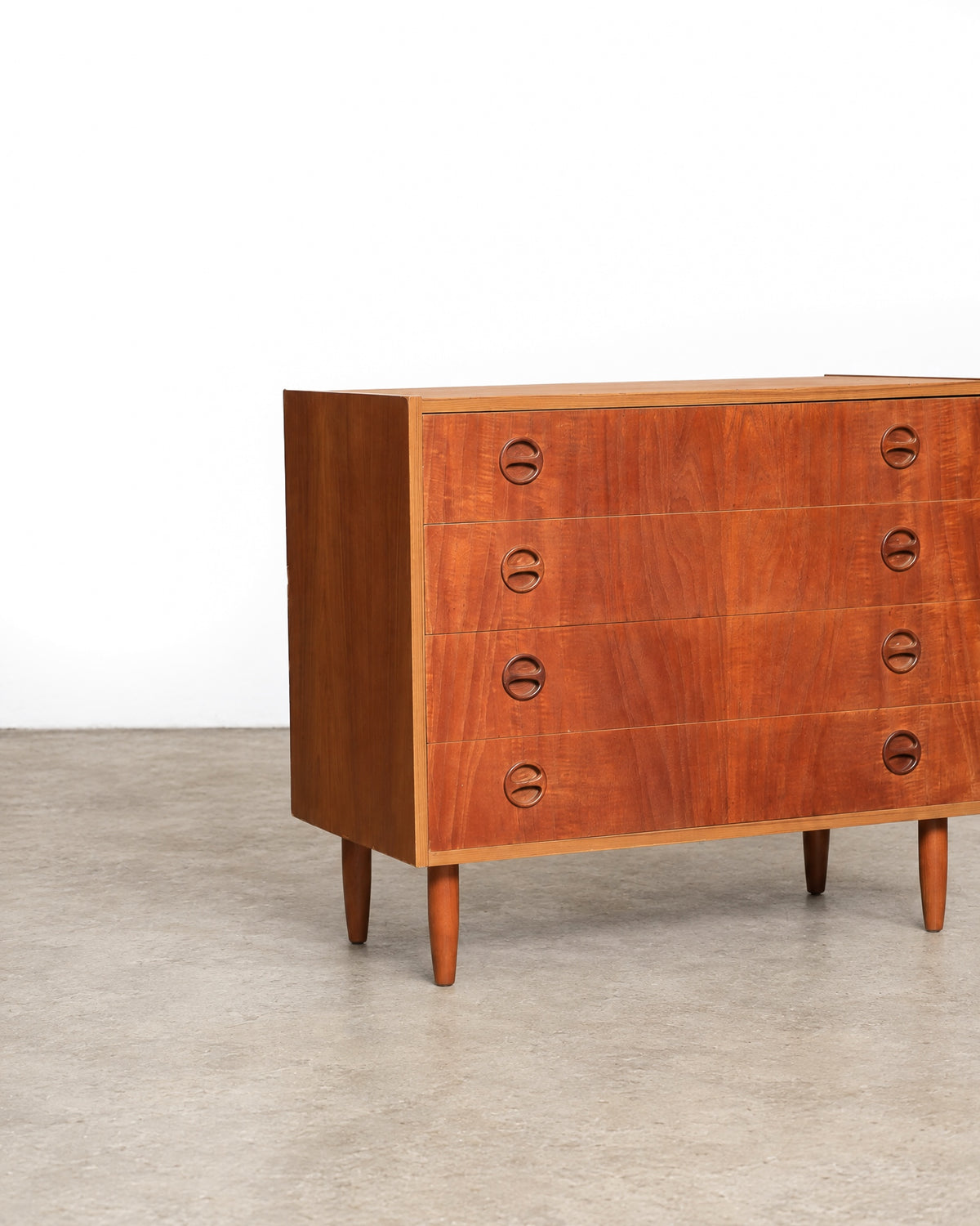 Close-up angle of the dresser's front left corner showing tapered legs and pulls.