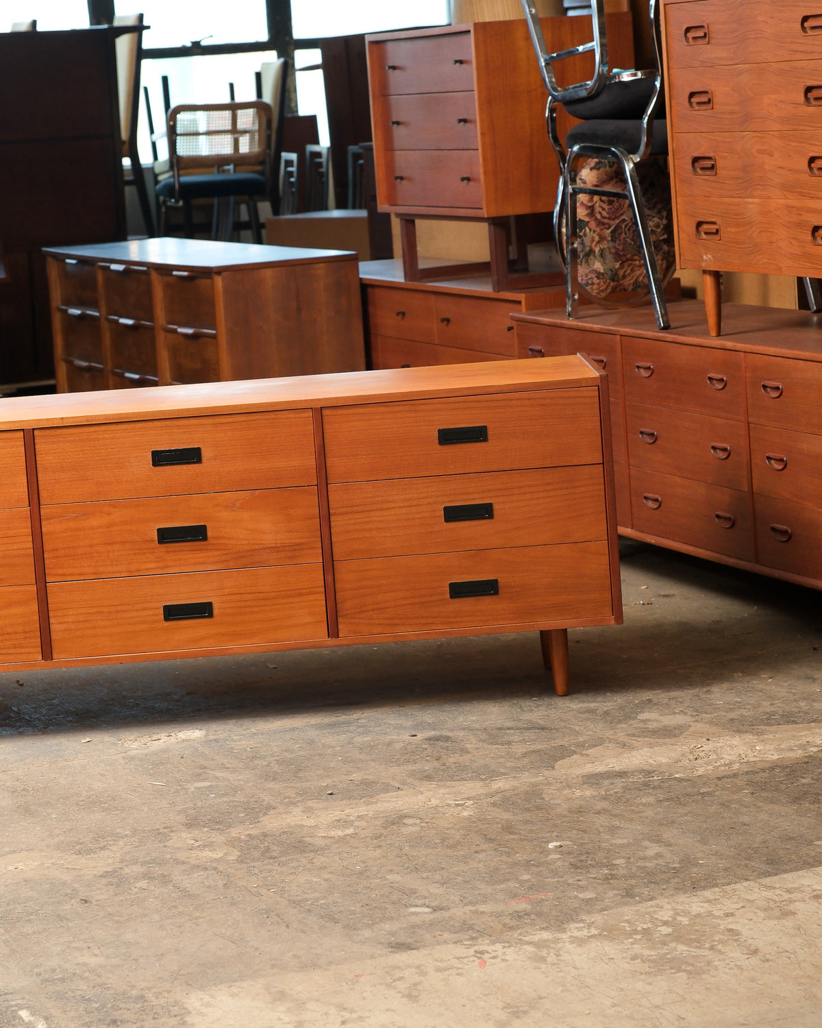 Close-up angled view of two drawer sections with black rectangular pulls and teak grain