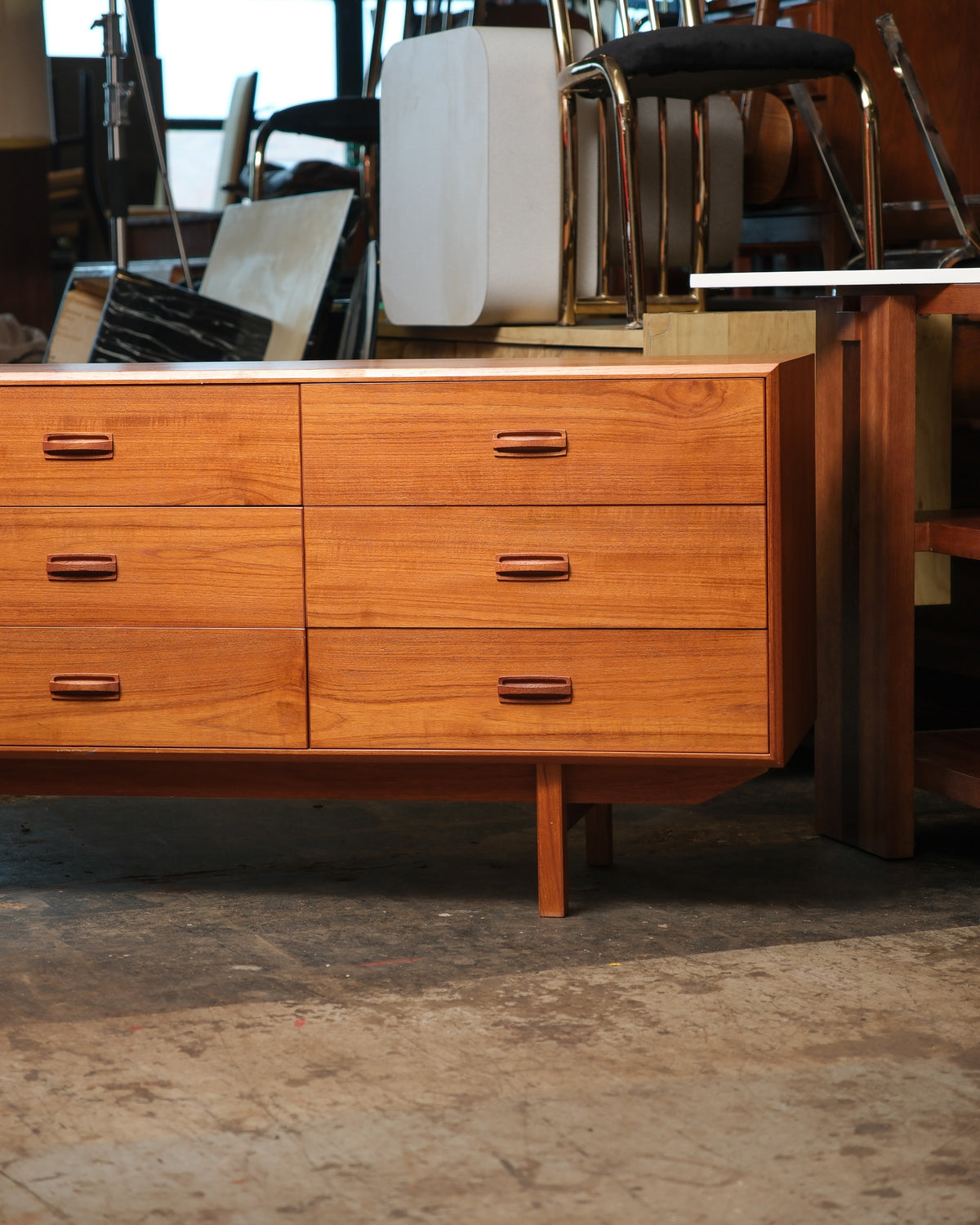 Front view of a mid-century modern teak 9-drawer dresser with sculpted wood pulls and tapered legs.