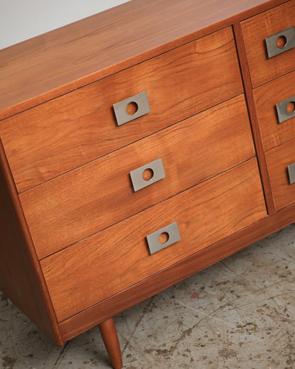 Angled view of the drawer front grouping with squared chrome knob pulls and tapered leg visible.
