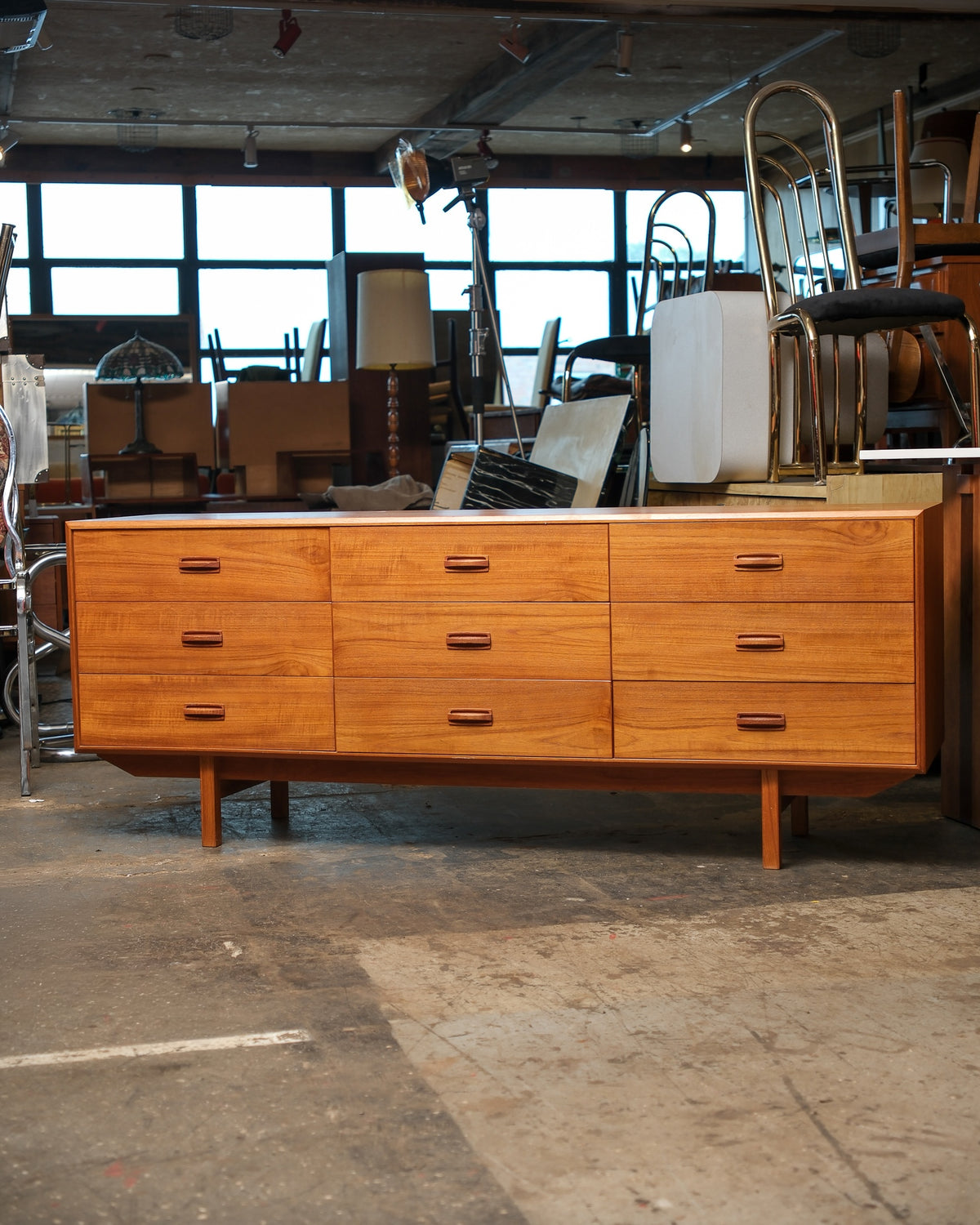 Full front view of the teak 9-drawer dresser showing three rows of nine drawers and a low, angled leg design.