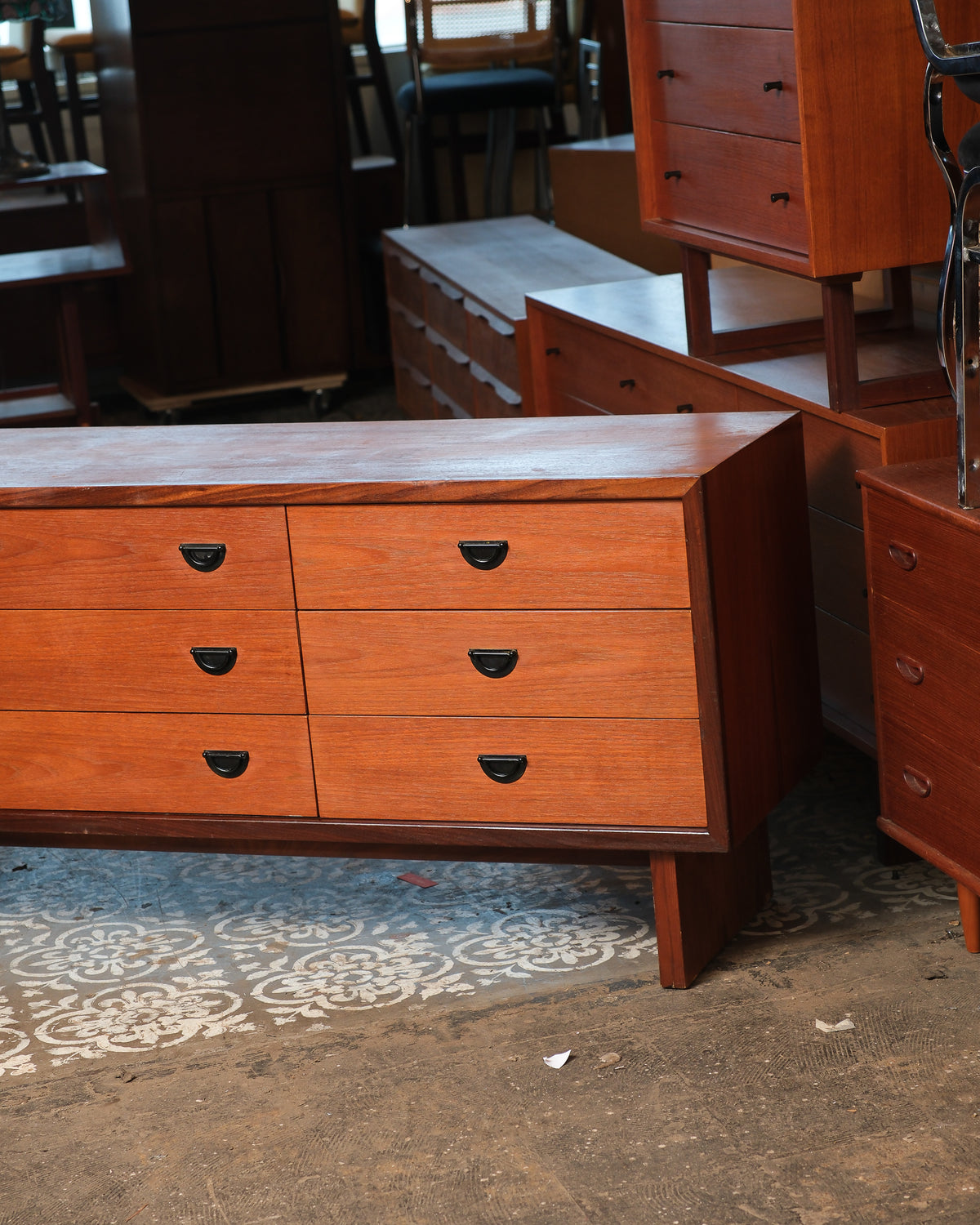 Close-up angled view of the dresser's front right corner showing teak grain and black half-moon pulls.