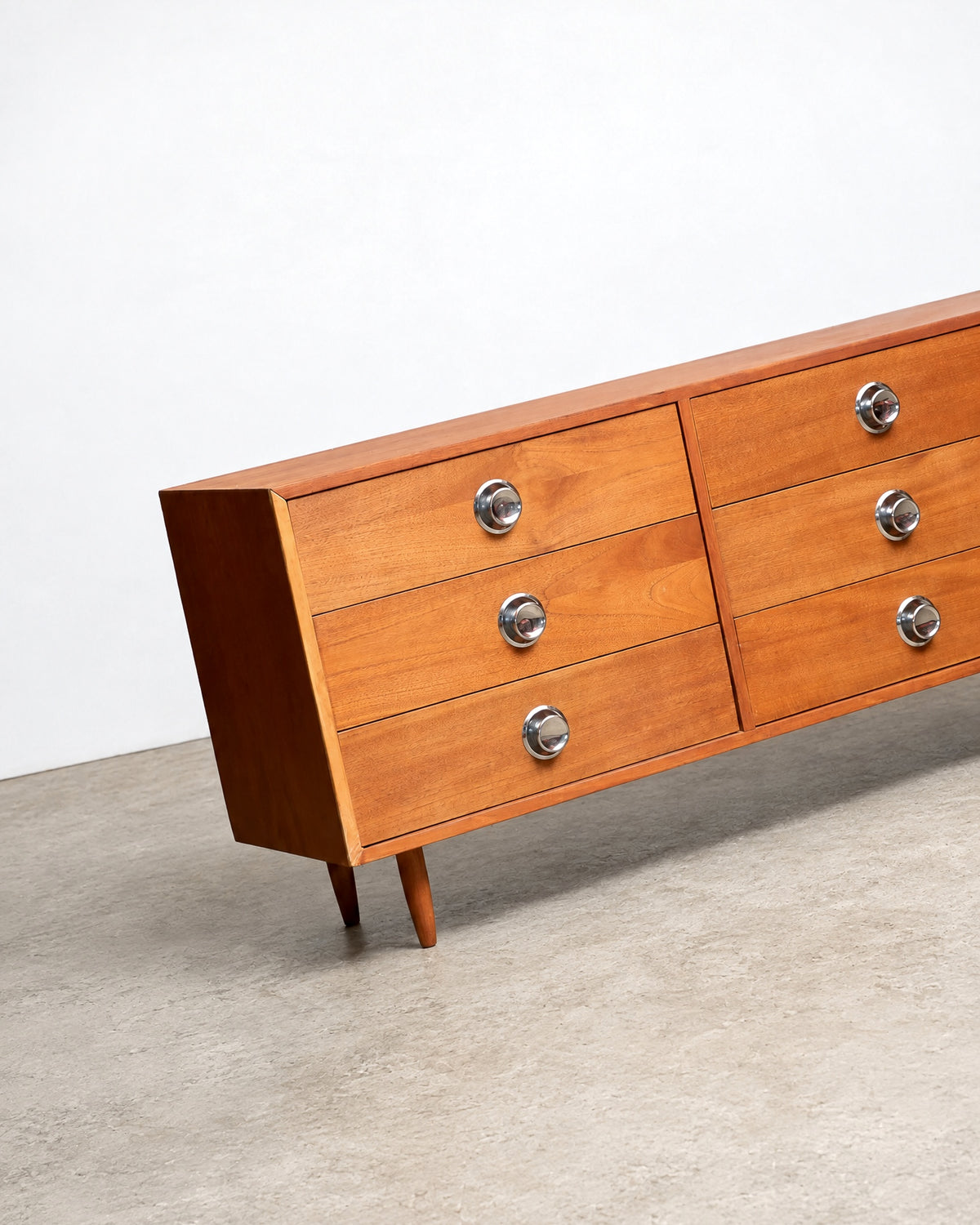 Front corner view of the dresser against a white background, showing tapered legs and knob detail.