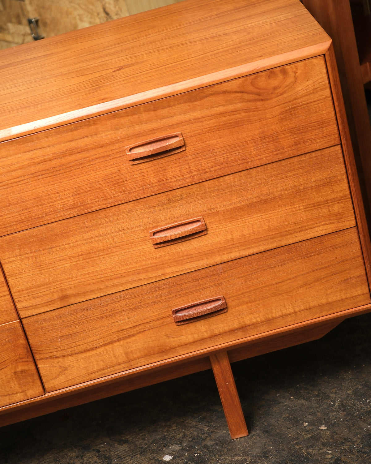 Close-up of the top left corner showing drawer fronts, pulls, and tapered leg detail.