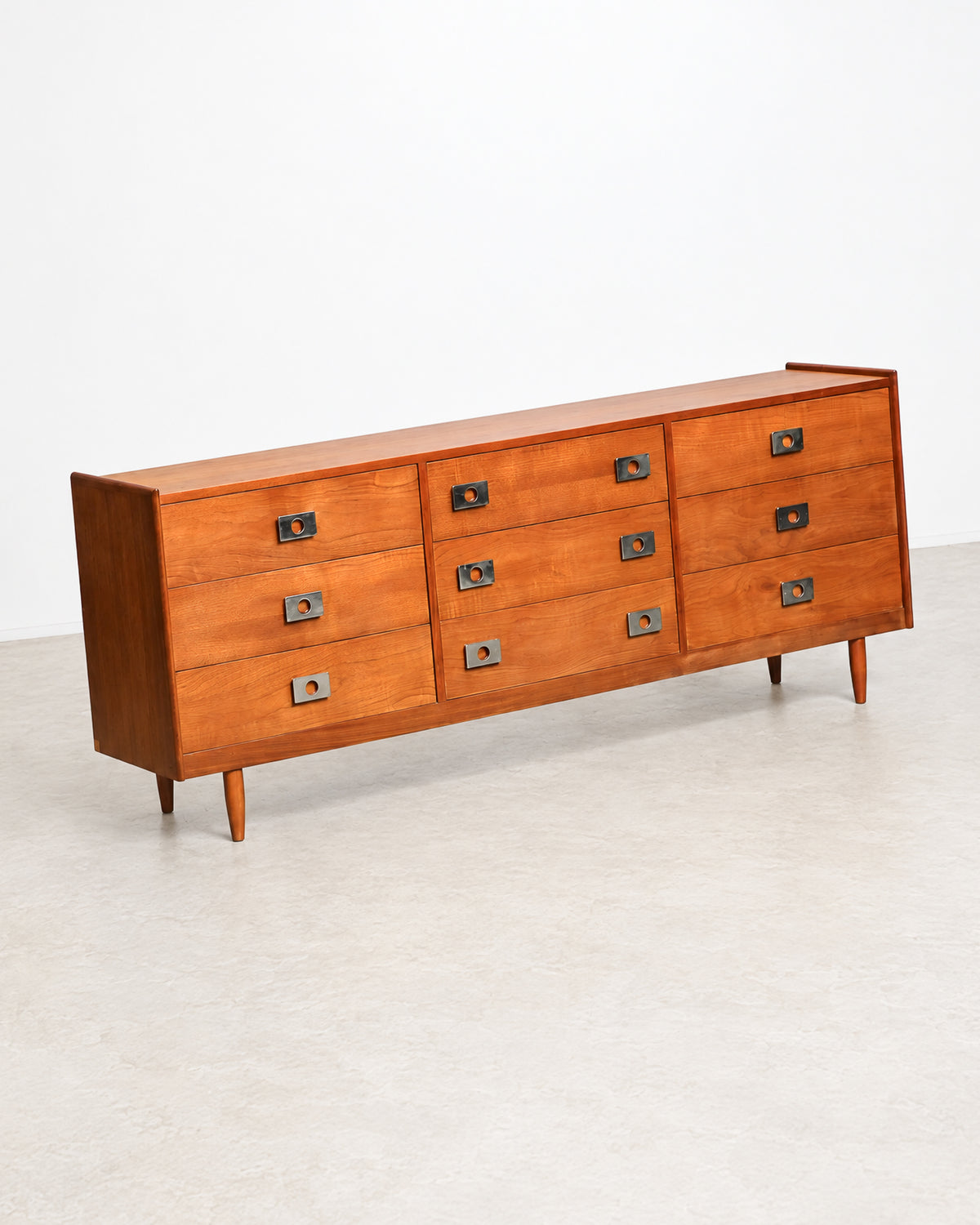 Front view of the full dresser showing all nine drawers and tapered legs.