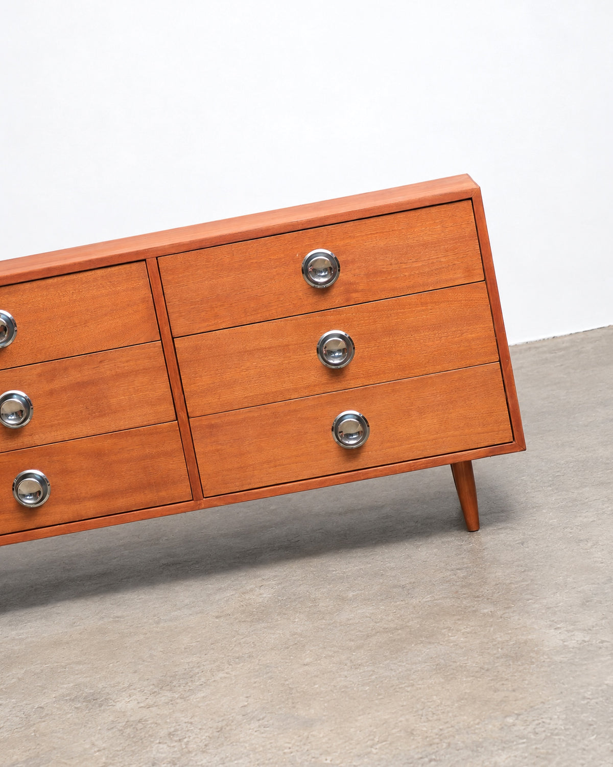 Detail view of the dresser's lower cabinet door and chrome pulls.