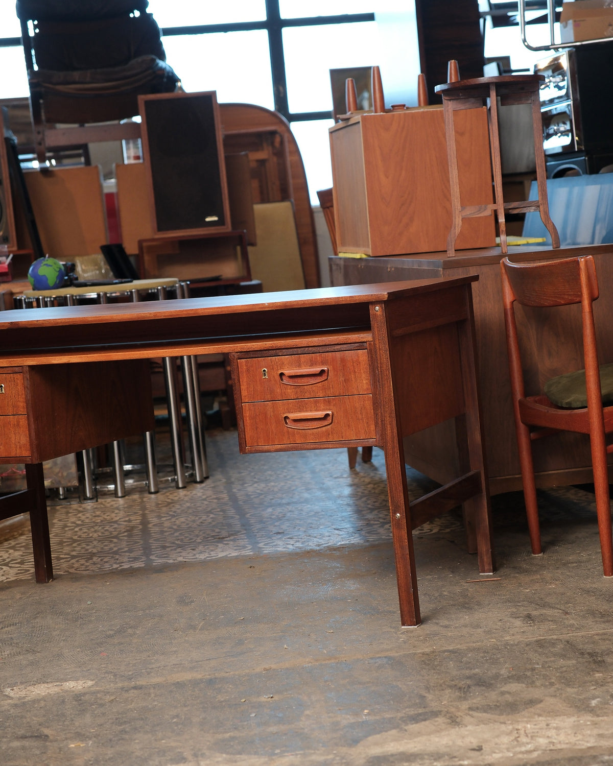 Side view of the teak desk showing the drawer bank and angled leg detail.
