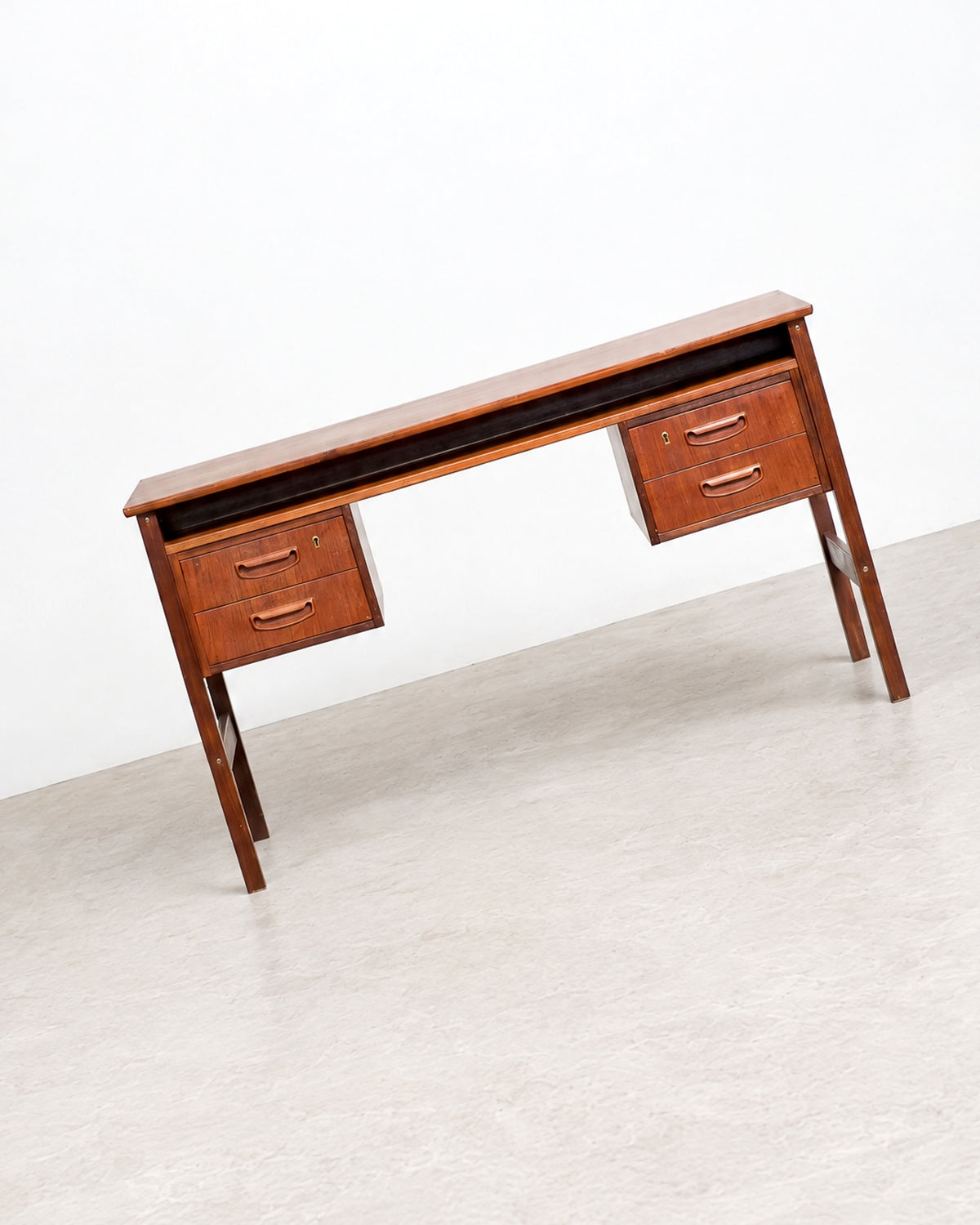 Three-quarter view of the teak desk on a plain background, showing both drawer pedestals and the floating top.