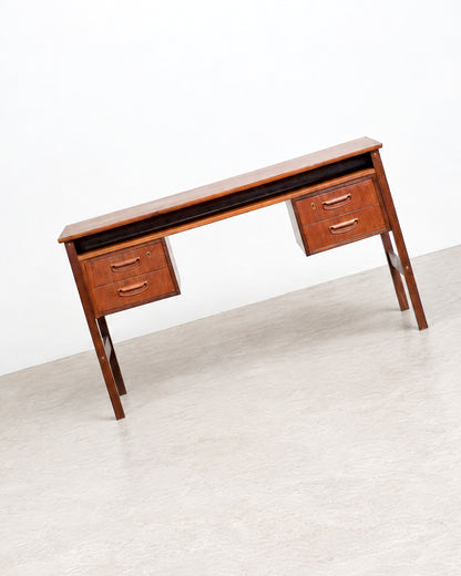 Three-quarter view of the teak desk on a plain background, showing both drawer pedestals and the floating top.