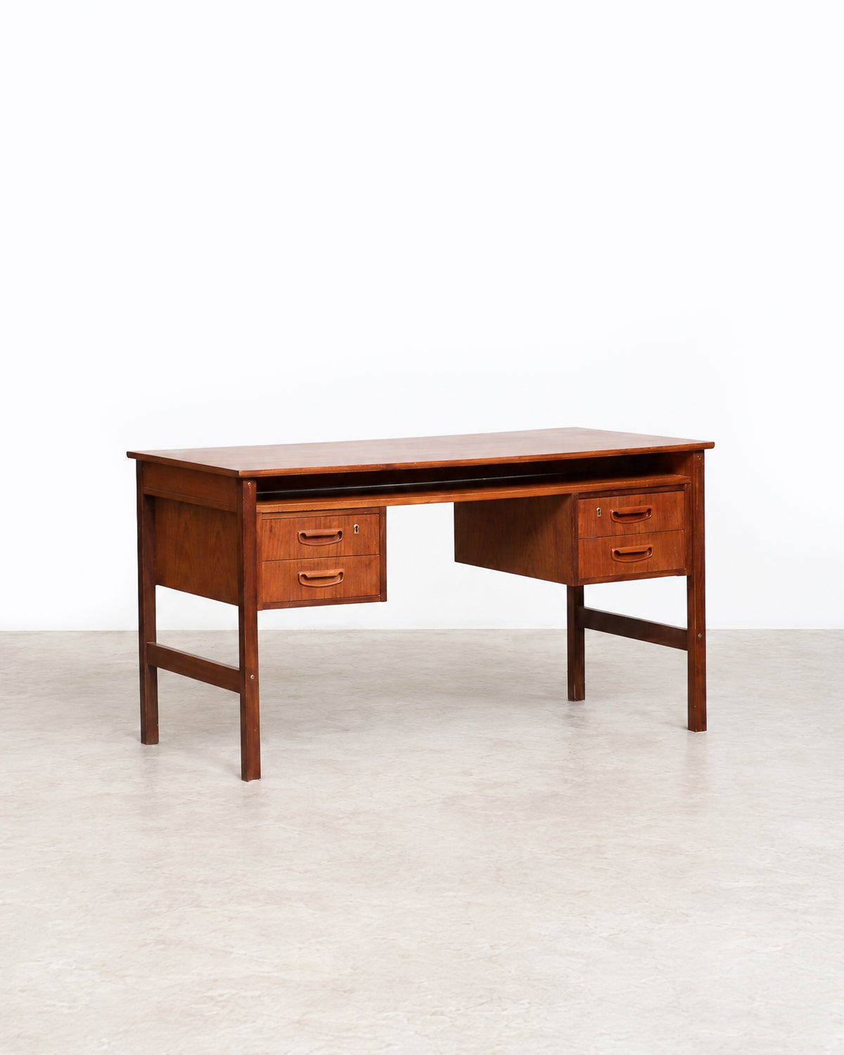 Rear or side angle of the teak desk showing overall construction and leg bracing.