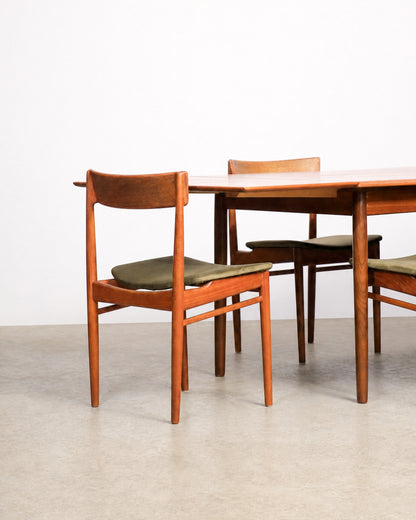 Side view of teak dining chair beside extendable table with leaf seam visible
