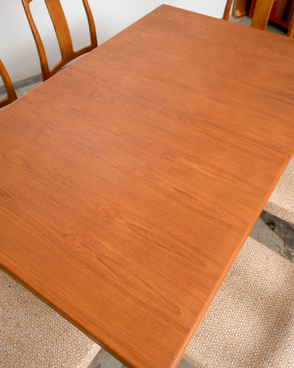 Close-up of the teak dining table surface showing the natural wood grain and leaf seam