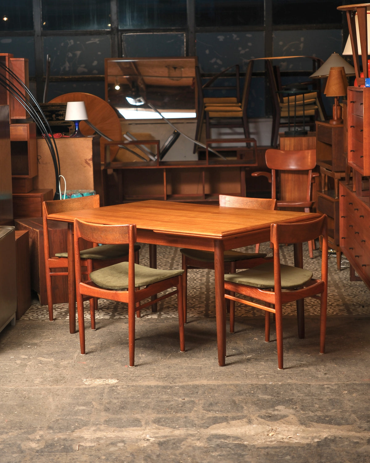 Full view of teak dining table with five chairs set in showroom
