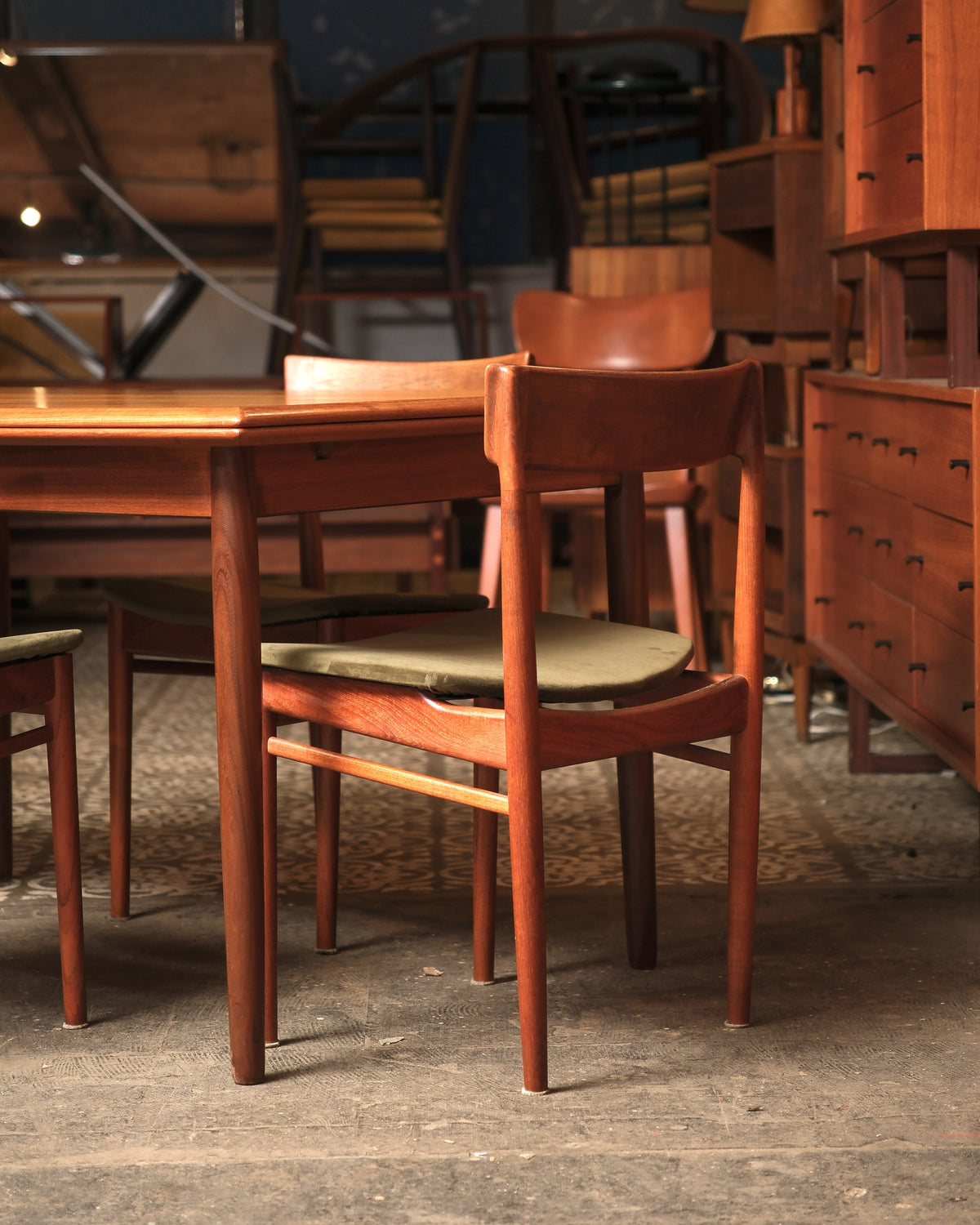 Front view of the extended teak dining table with chairs arranged around it