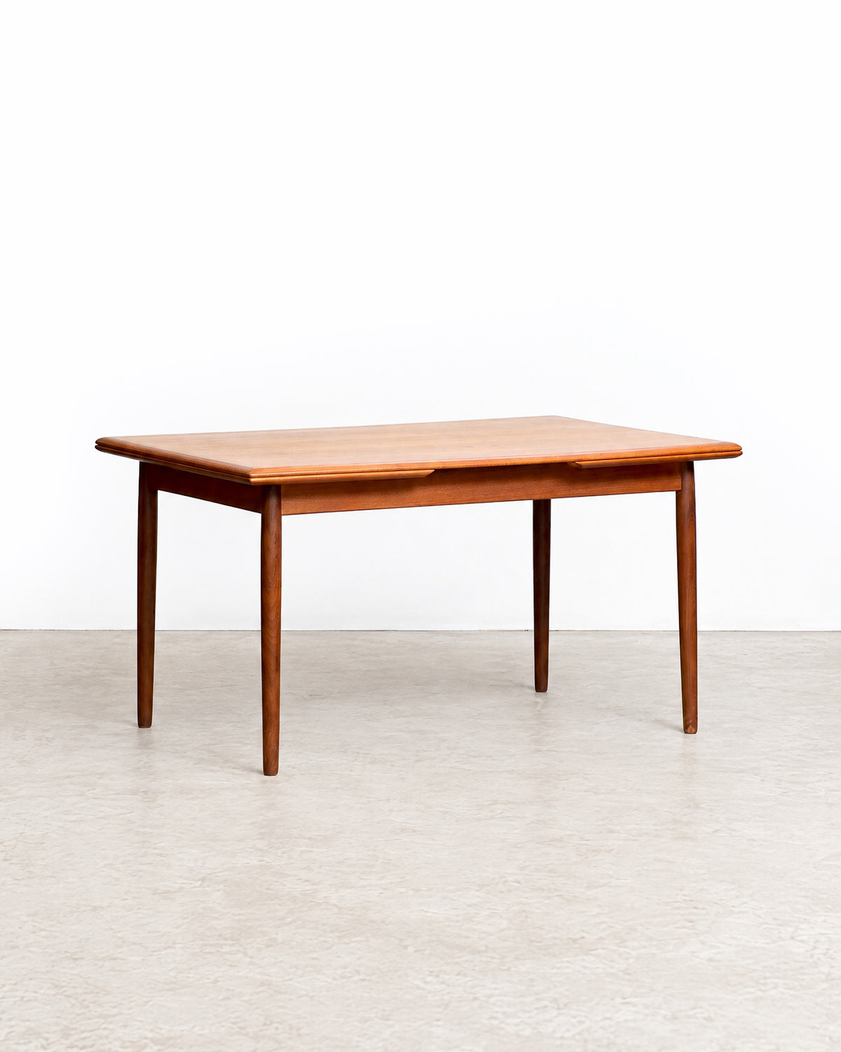 Wide view of the teak dining table in the showroom setting among other vintage pieces.