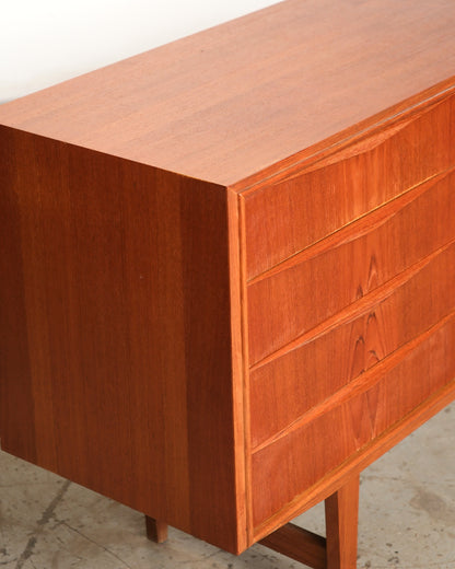 Close-up angled view of the teak sideboard corner showing drawer fronts and grain detail.