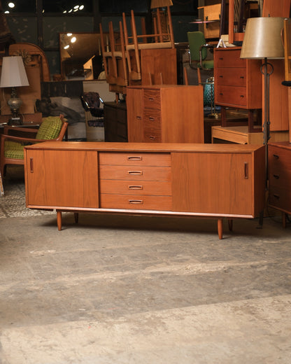 Mid-century modern teak sideboard with sliding doors and central drawers, shown in the showroom
