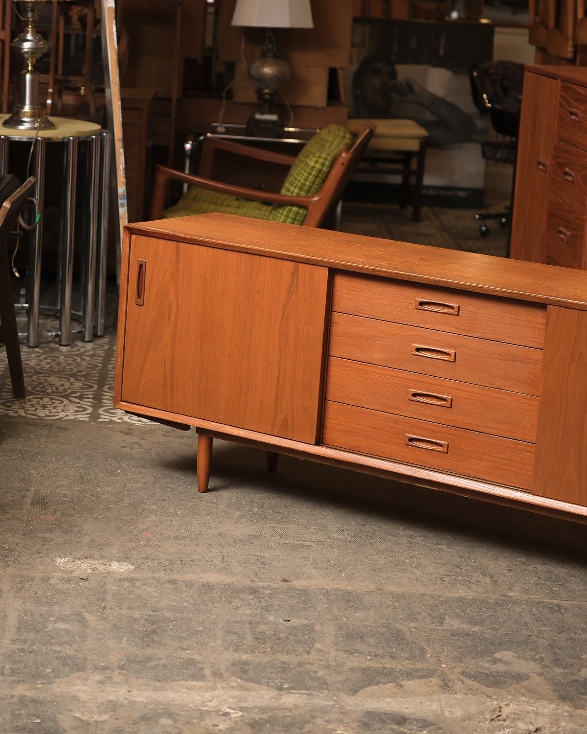 Angled view of the sideboard showing the sliding door, drawer pulls, and tapered leg