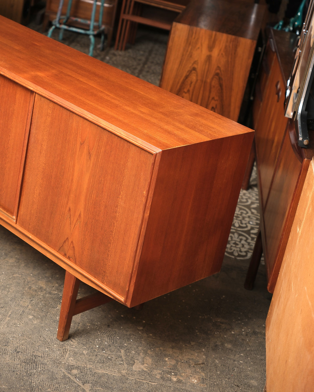 Angled view of the opposite end of the sideboard showing sliding doors and tapered leg.