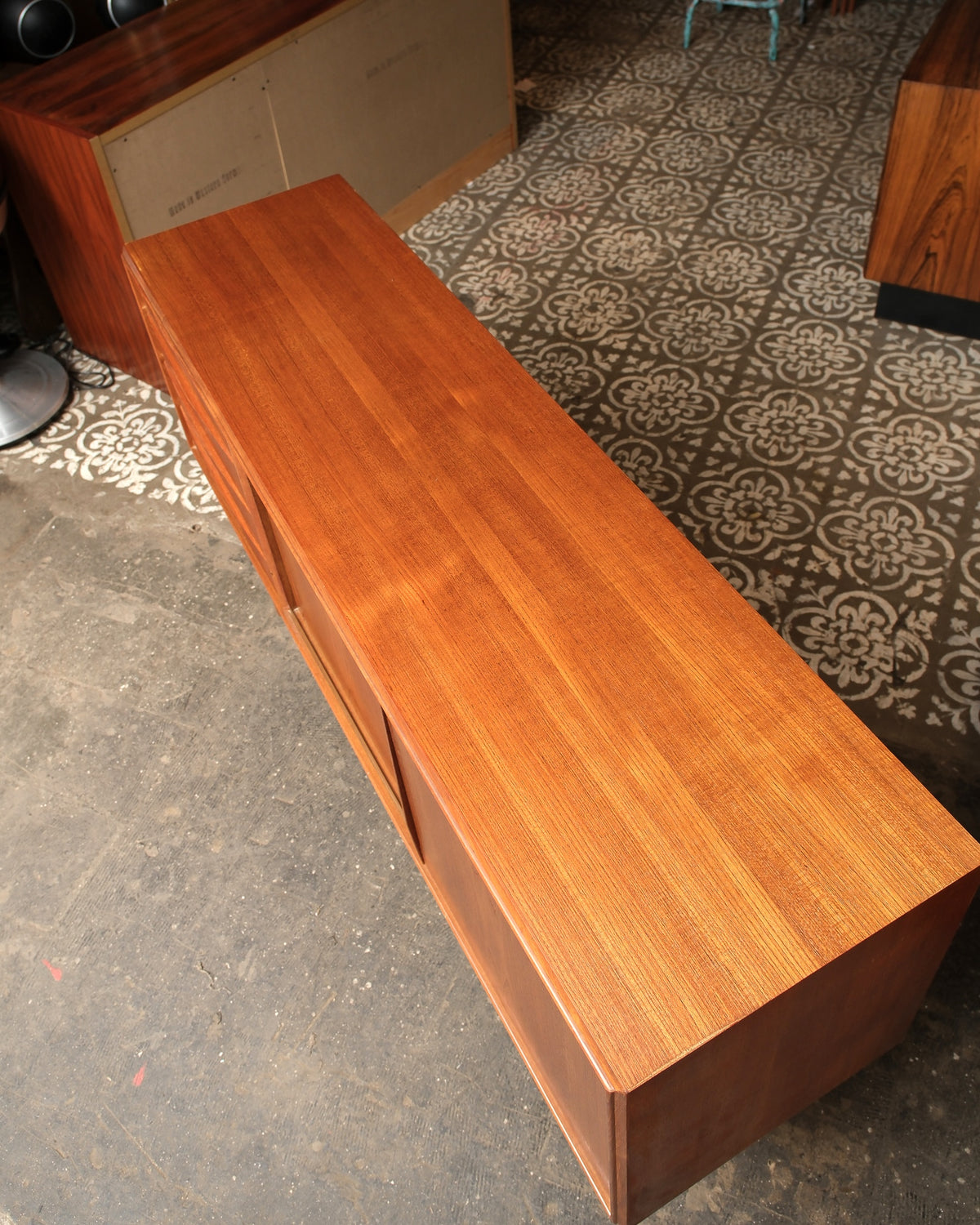 Overhead view of the sideboard top showing continuous teak grain and sliding door seams.