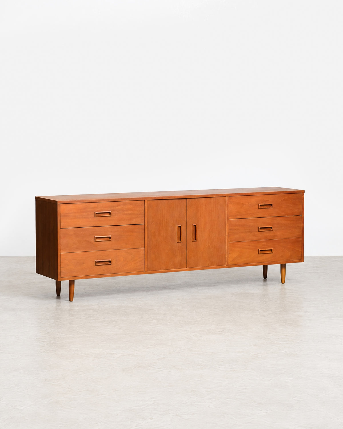 Full view of the teak sideboard in the showroom setting among other vintage furniture.