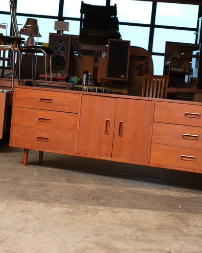 Front view of the teak sideboard showing three drawers on each side flanking a central two-door cabinet.
