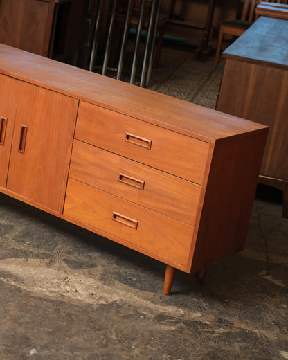 Close-up angled view of the drawer bank and tapered leg on one end of the teak sideboard.