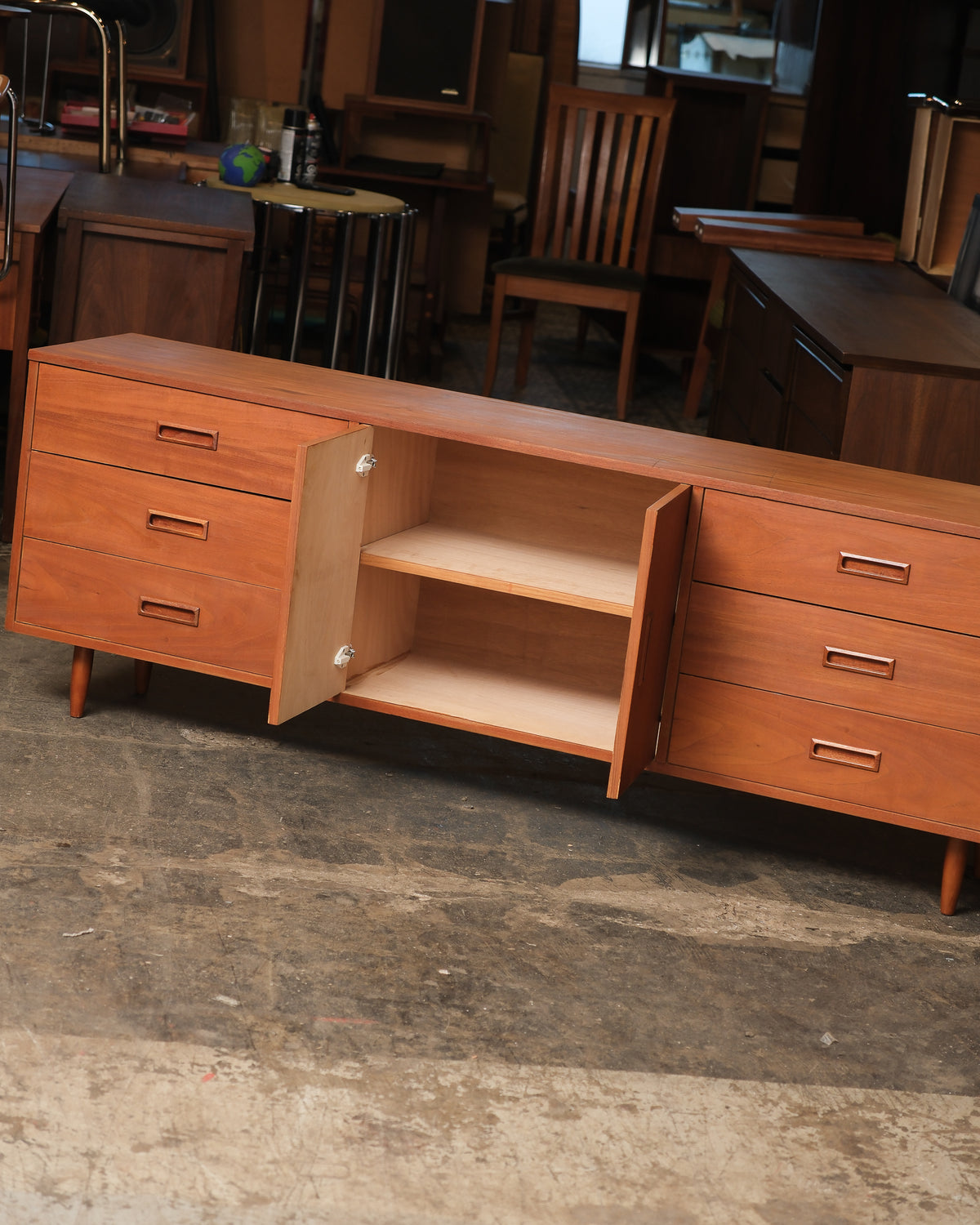 Interior view of the center cabinet opened to reveal an adjustable shelf, flanked by drawers.