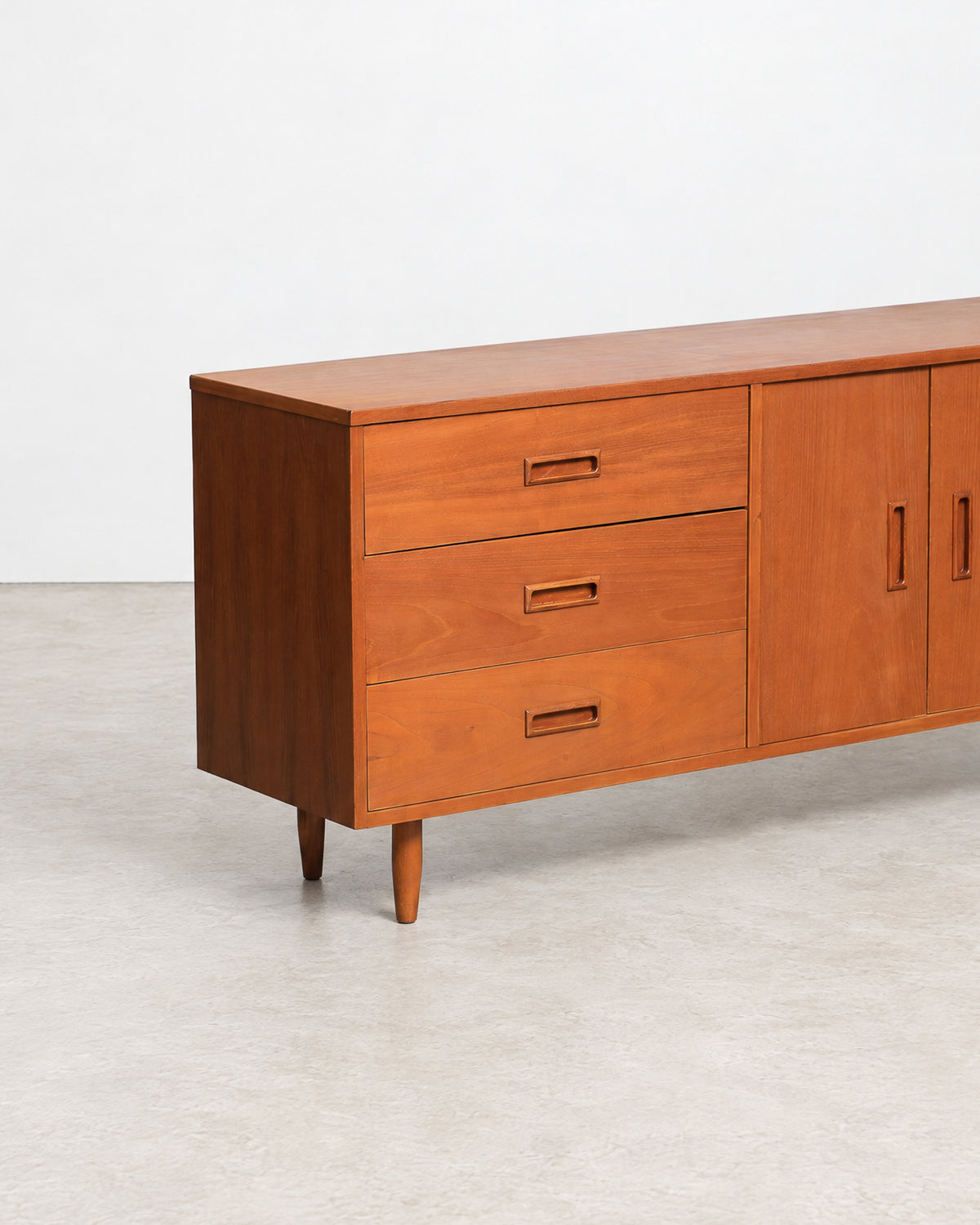 Close-up of a sculpted recessed drawer pull on the teak sideboard.