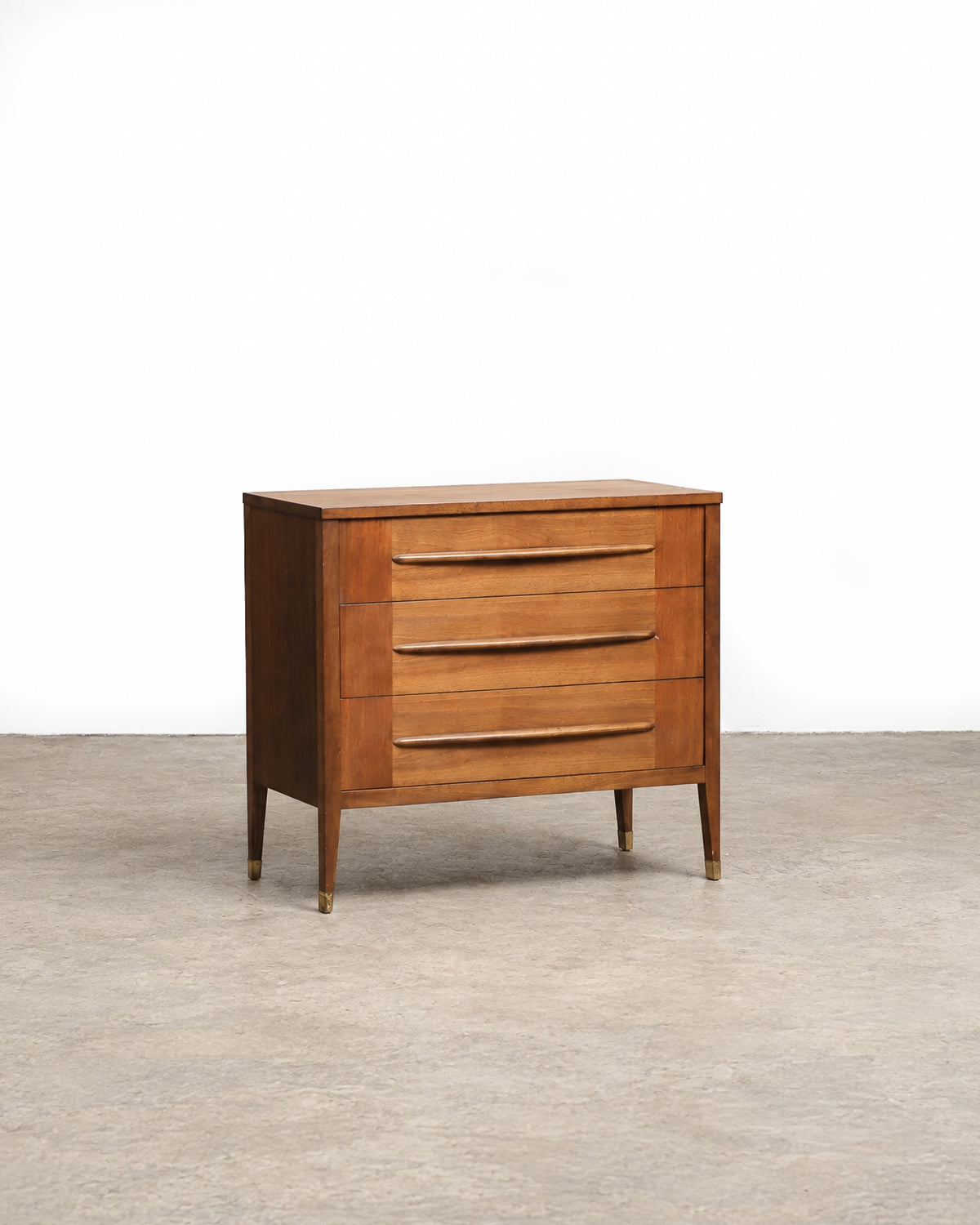 Front angled view of the walnut 3-drawer dresser with tapered legs and brass feet