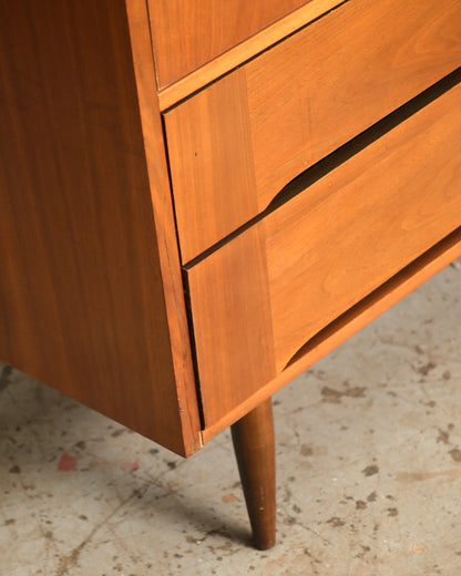 Close-up of the lower right corner showing tapered leg, drawer pull detail, and walnut grain.