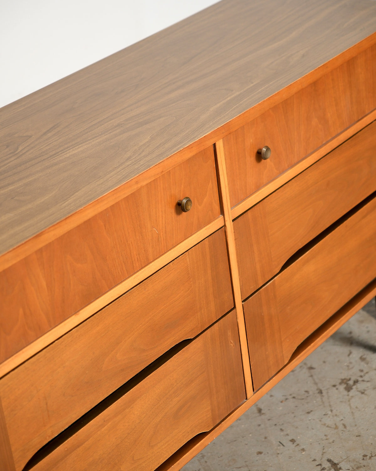Angled view of the top corner showing brass knobs, drawer joinery, and grain patterning across the top.
