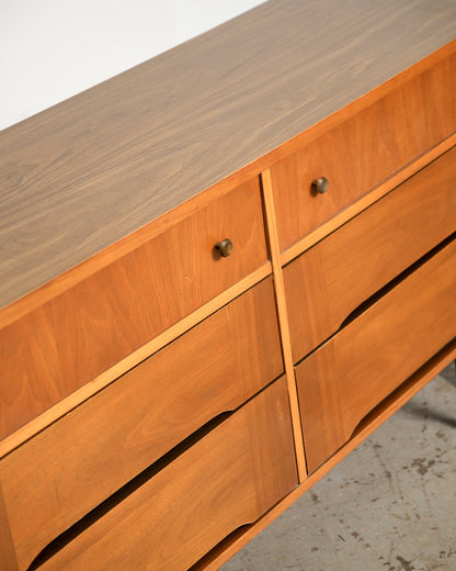 Angled view of the top corner showing brass knobs, drawer joinery, and grain patterning across the top.