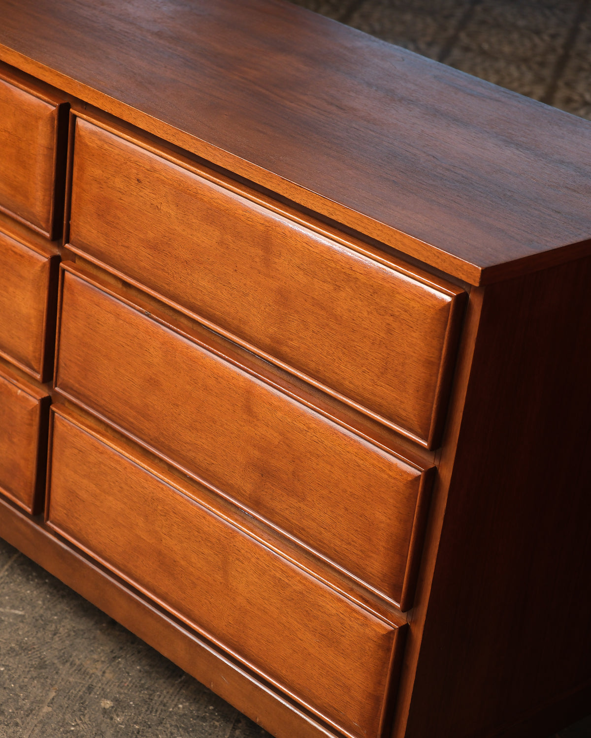Close-up angle of the dresser's upper drawers showing sculpted fronts and rich walnut grain.