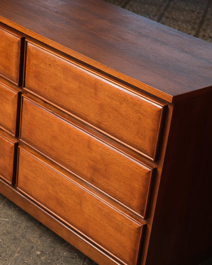 Close-up angle of the dresser's upper drawers showing sculpted fronts and rich walnut grain.