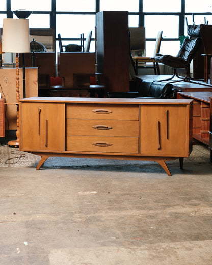 Mid-century modern walnut 9-drawer dresser, front view in showroom setting.