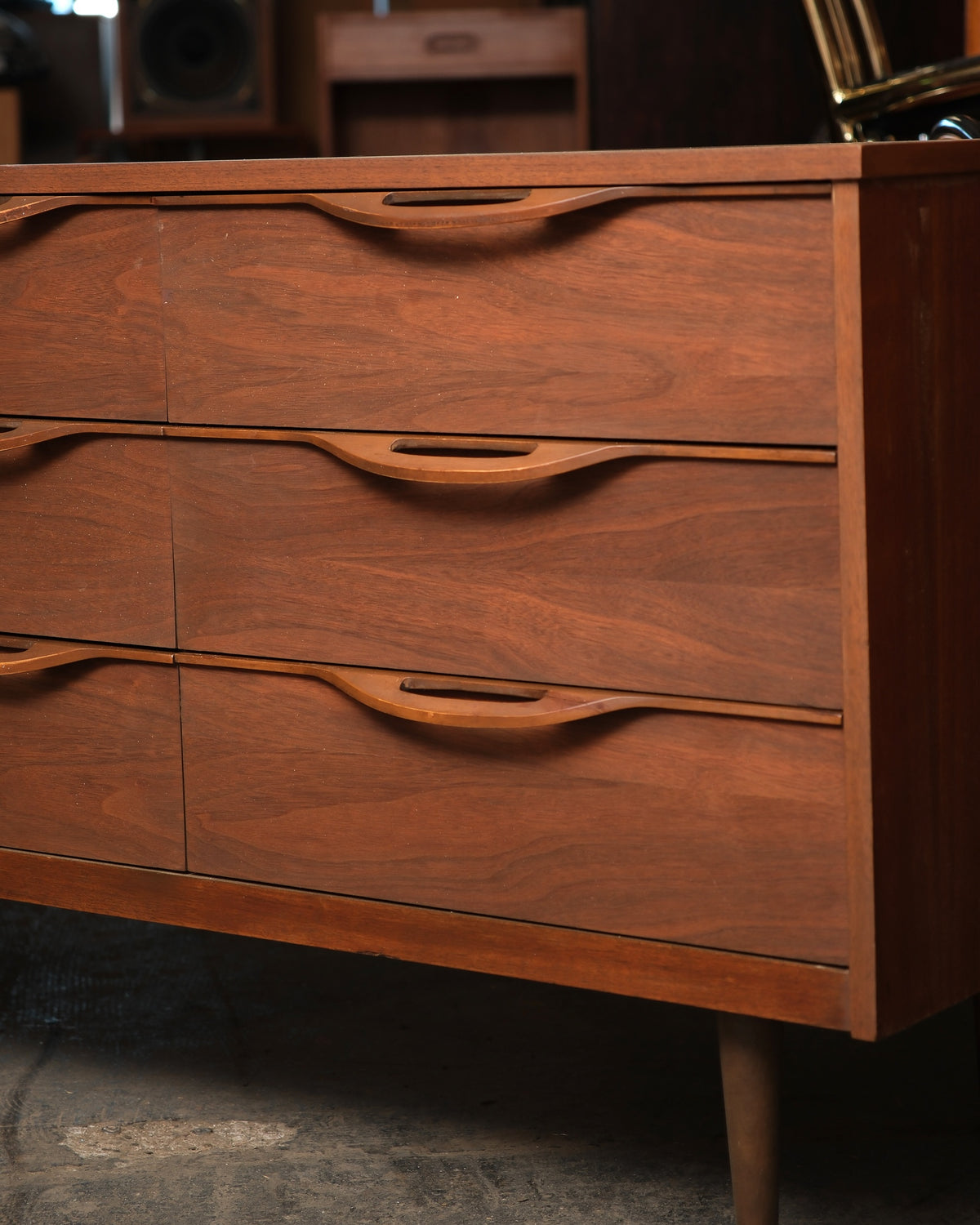 Close-up of three drawer fronts showing sculpted pull handles and walnut grain detail