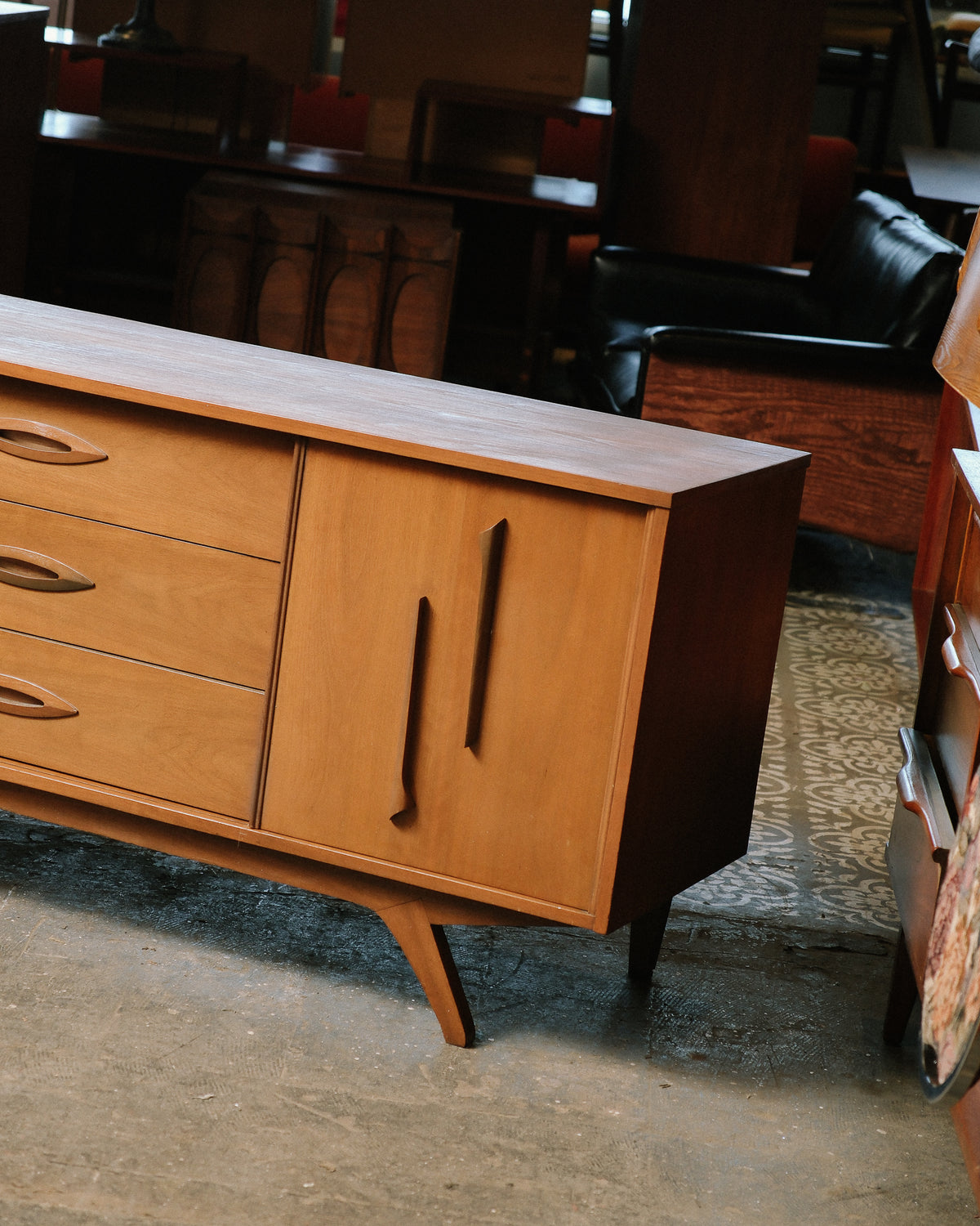 Close-up of side and drawer handles showing sculpted pull design and tapered leg.