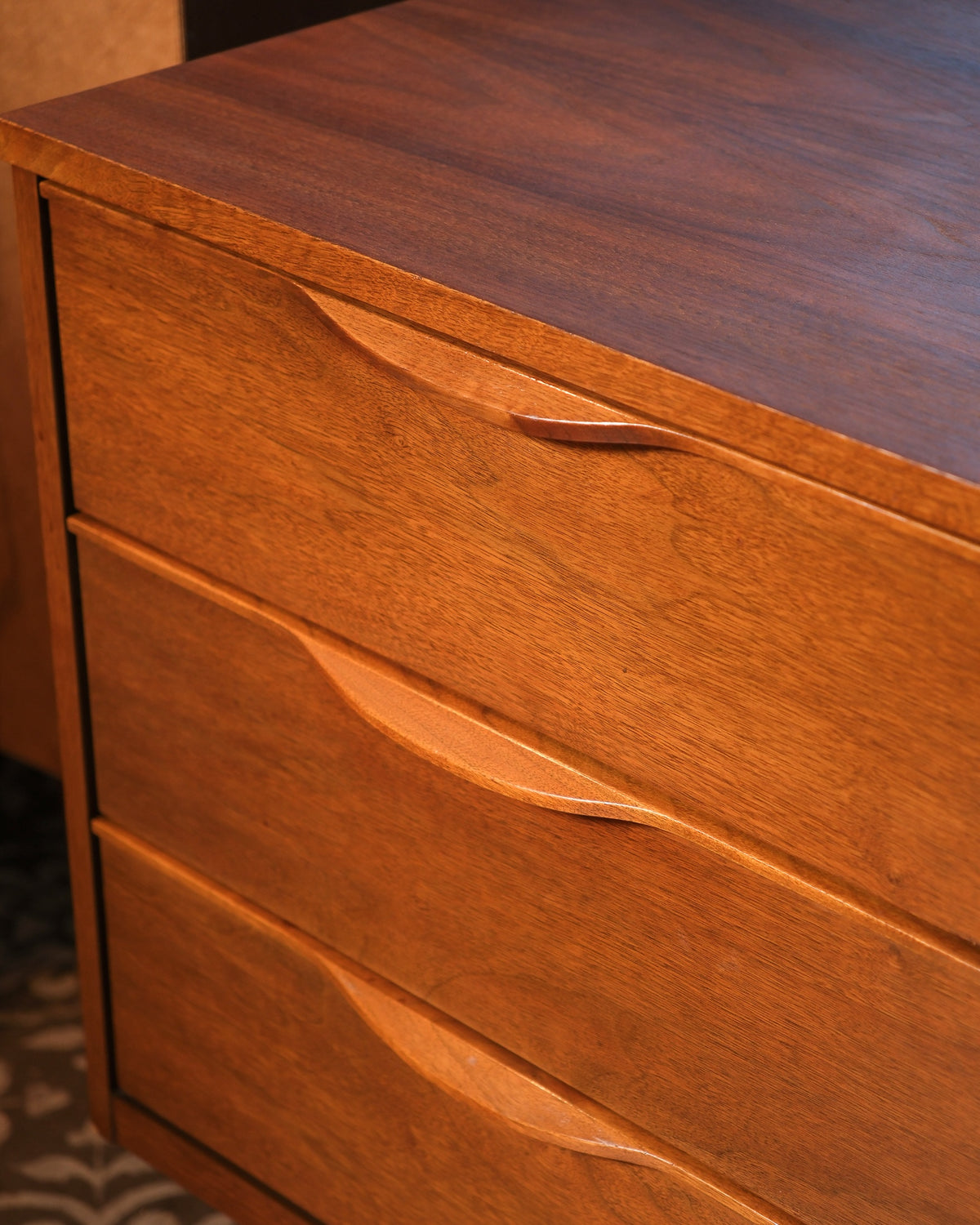 Close view of two sculpted drawer pulls and warm walnut wood grain.