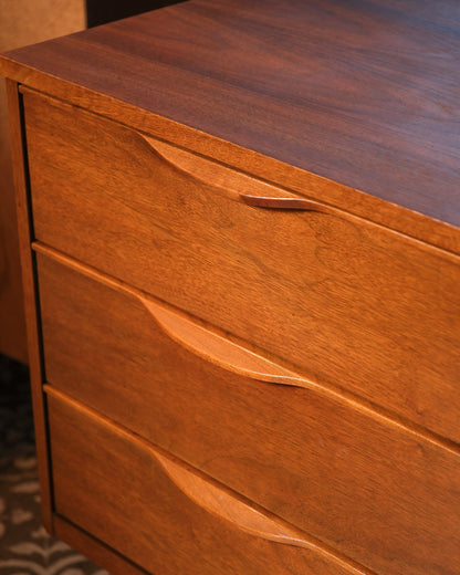 Close view of two sculpted drawer pulls and warm walnut wood grain.