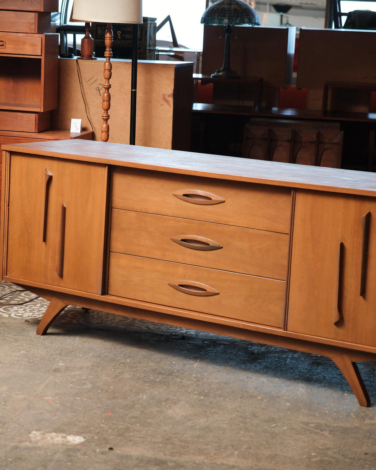Front angle view highlighting three center drawers and sliding cabinet doors.