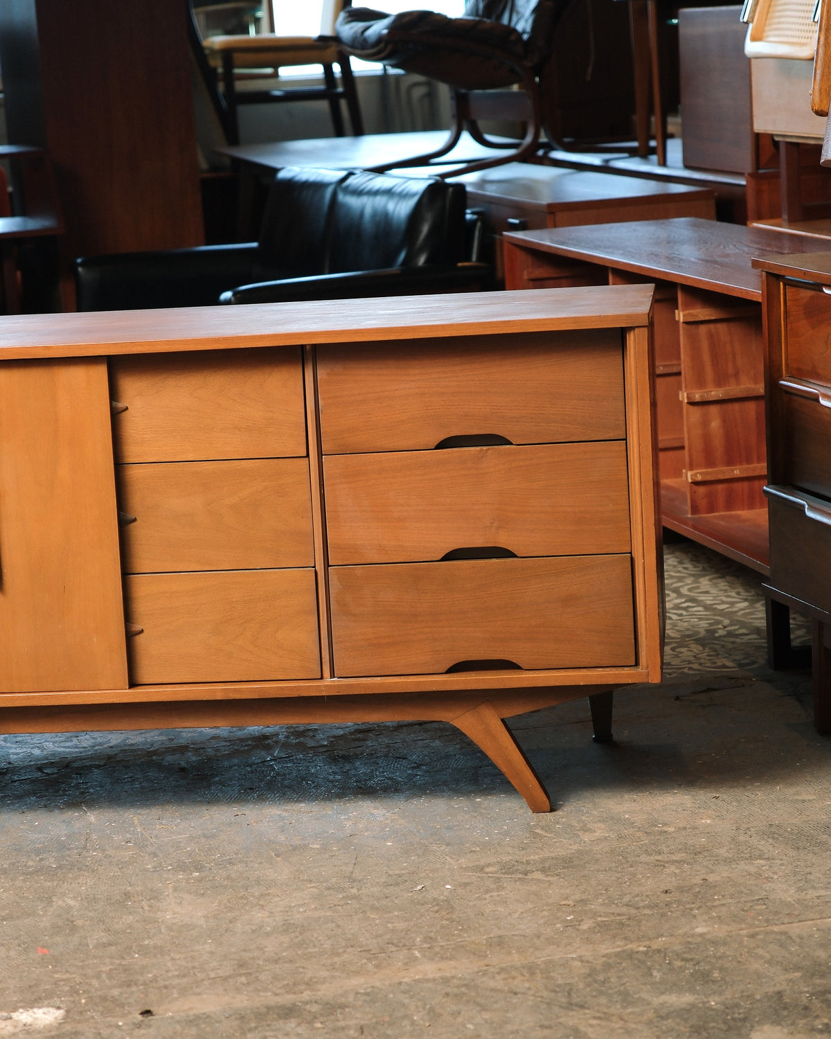 Detail of open side cabinet revealing three interior drawers with wood pulls.
