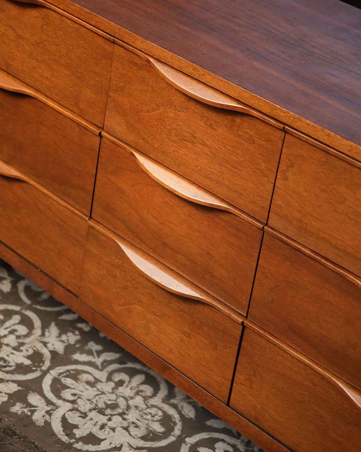 Overhead close-up of drawer pulls and walnut grain across the dresser front.