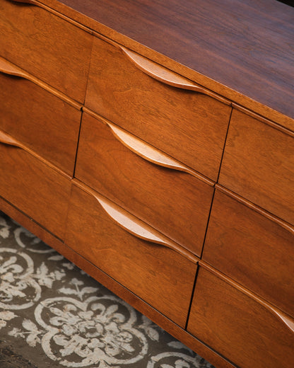 Overhead close-up of drawer pulls and walnut grain across the dresser front.