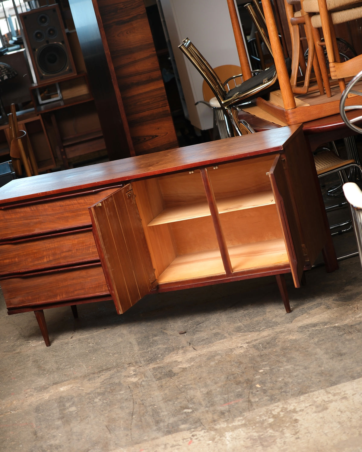 Mid-century modern walnut credenza with one cabinet door open showing adjustable interior shelving