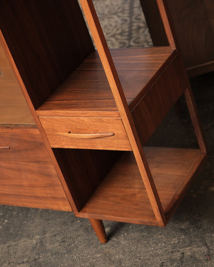 Close-up of the open shelf and drawer detail showing walnut grain and sculptural wood pulls.